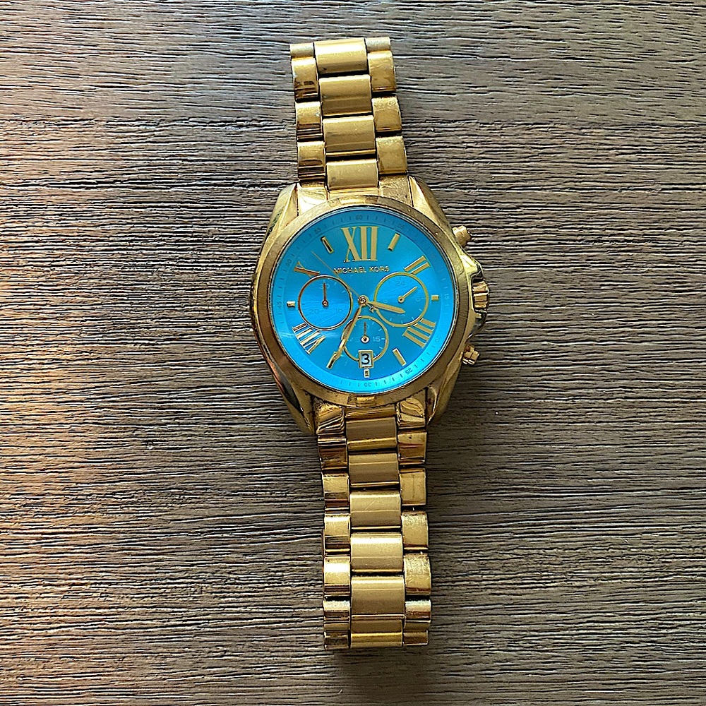 Micheal Kors woman’s gold watch with teal face